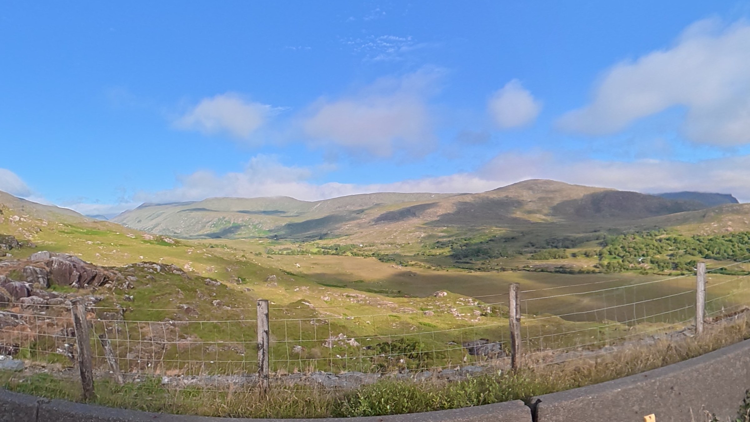 Sunlit mountains and green valley beside the road to Ladies View