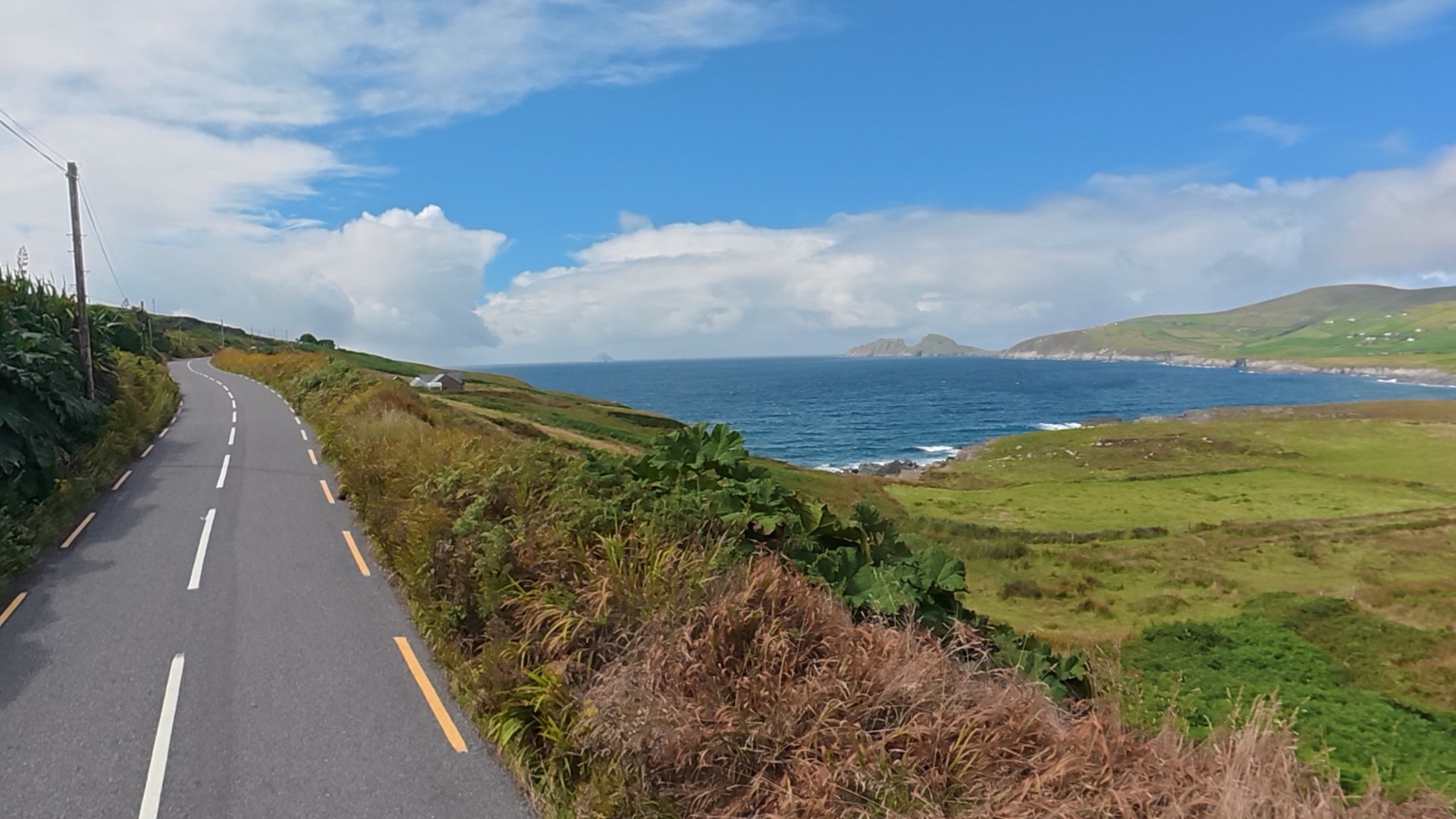 The Skellig Ring road beside green fields and blue coastal water