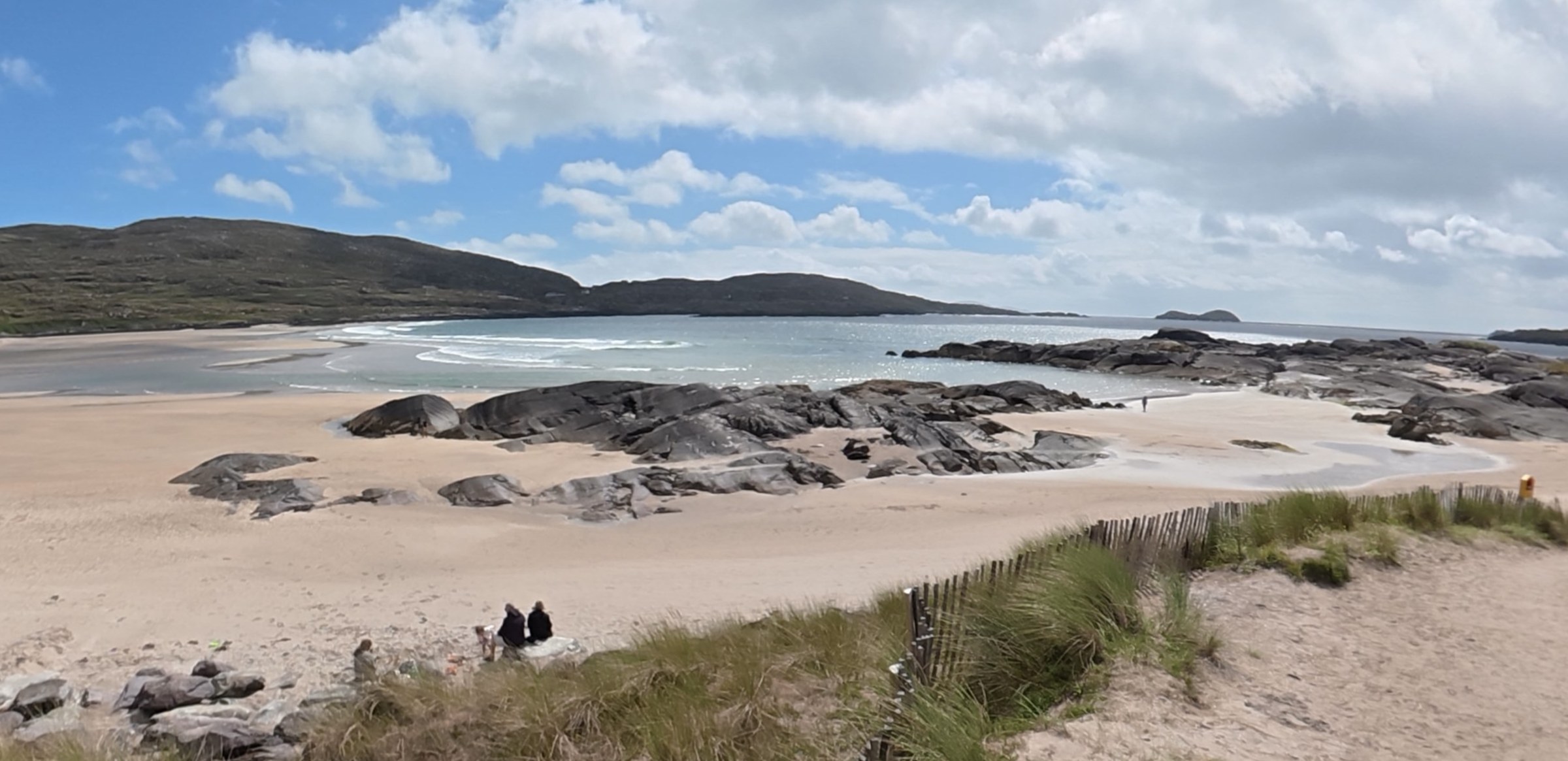 A panoramic view across the sand and rocks of Derrynane Beach