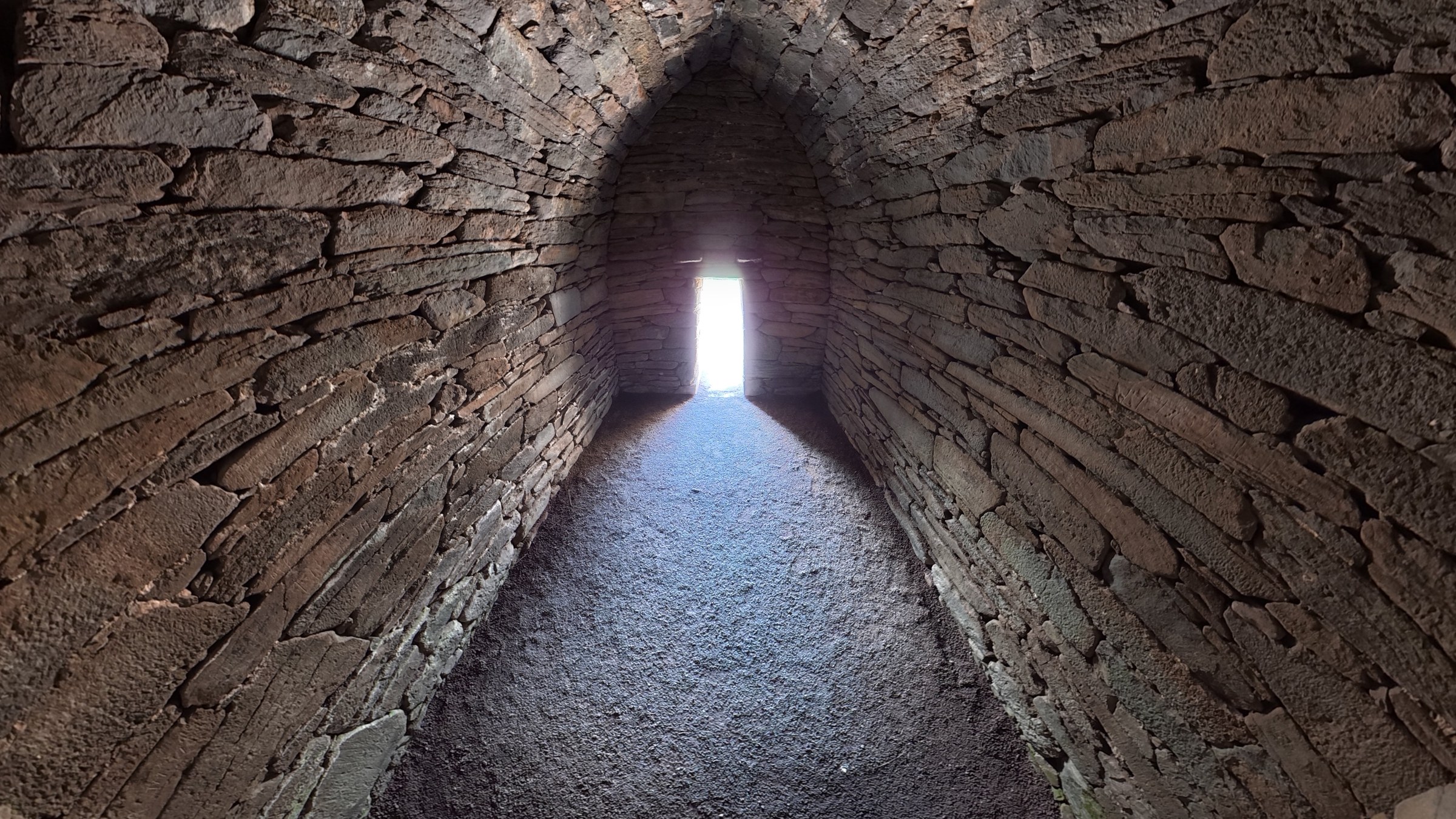 Light entering through the small window inside the dark Gallarus Oratory