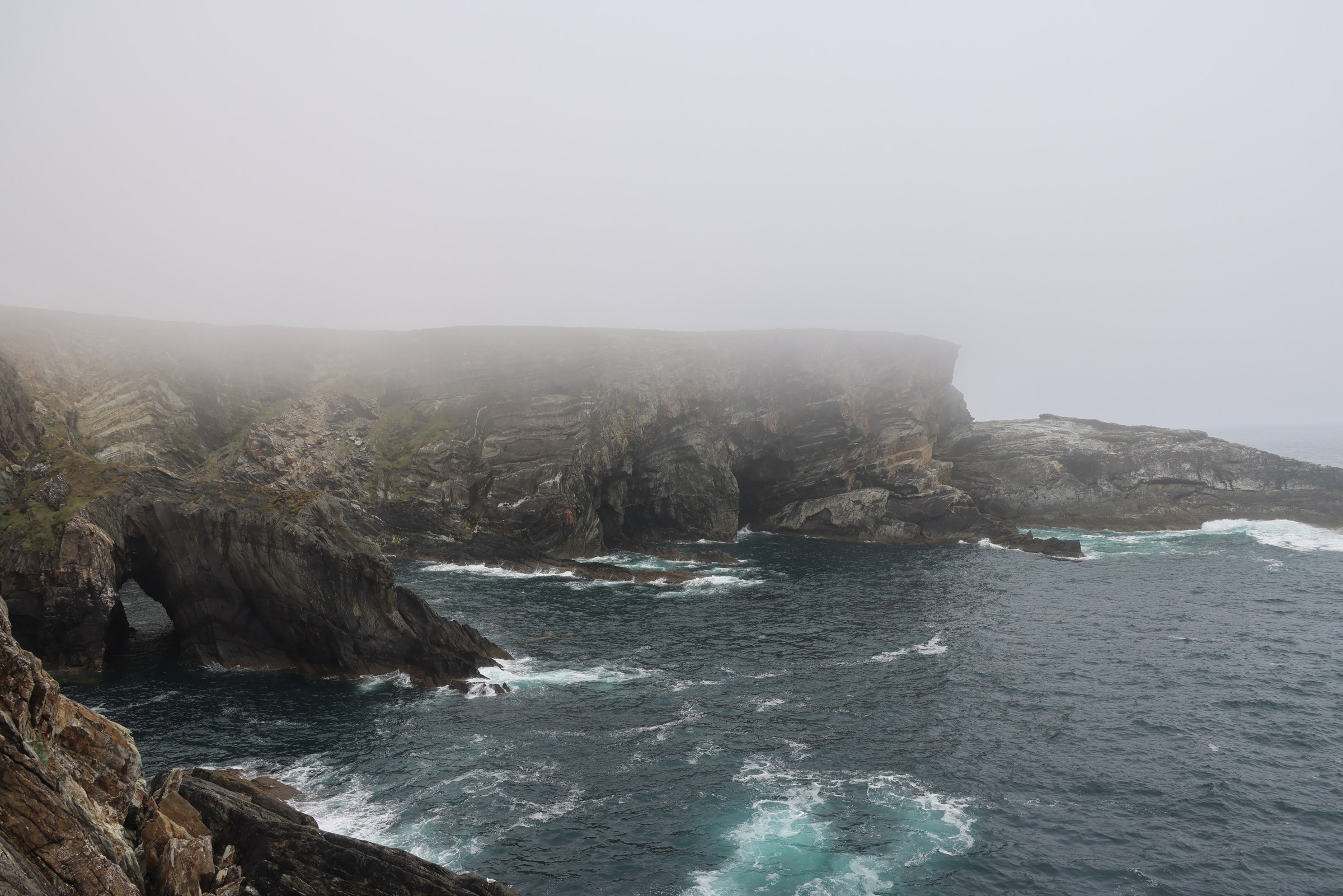 The rocky Atlantic coast disappearing into fog at Mizen Head