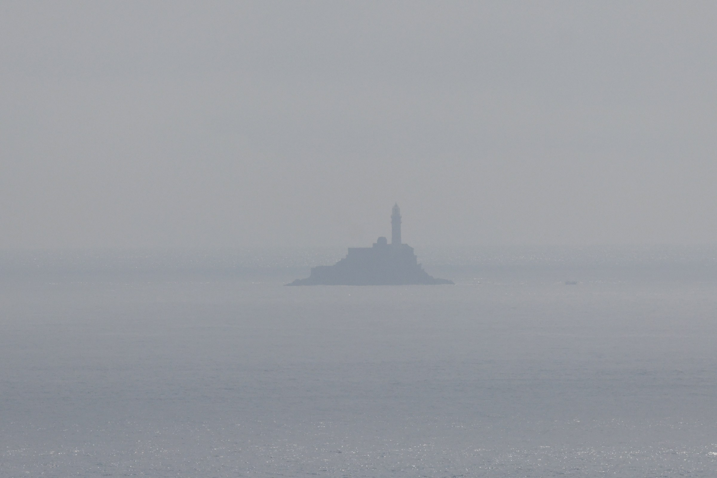 Fastnet Lighthouse appearing faintly through the haze offshore