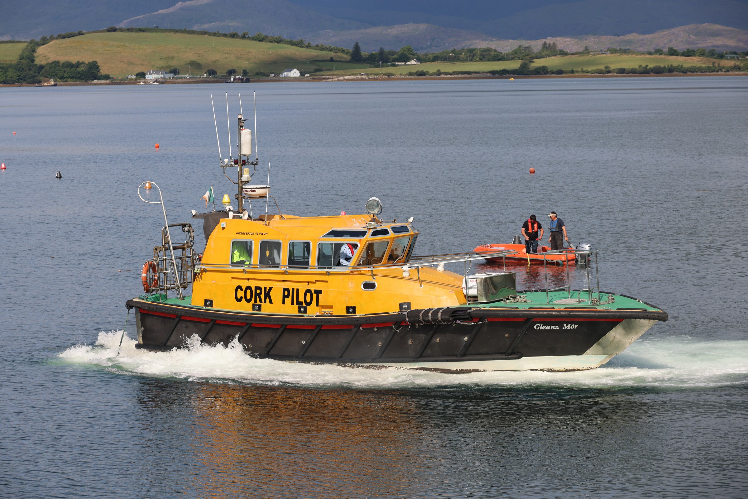 A yellow Cork pilot boat crossing Bantry Bay beside an orange rescue craft