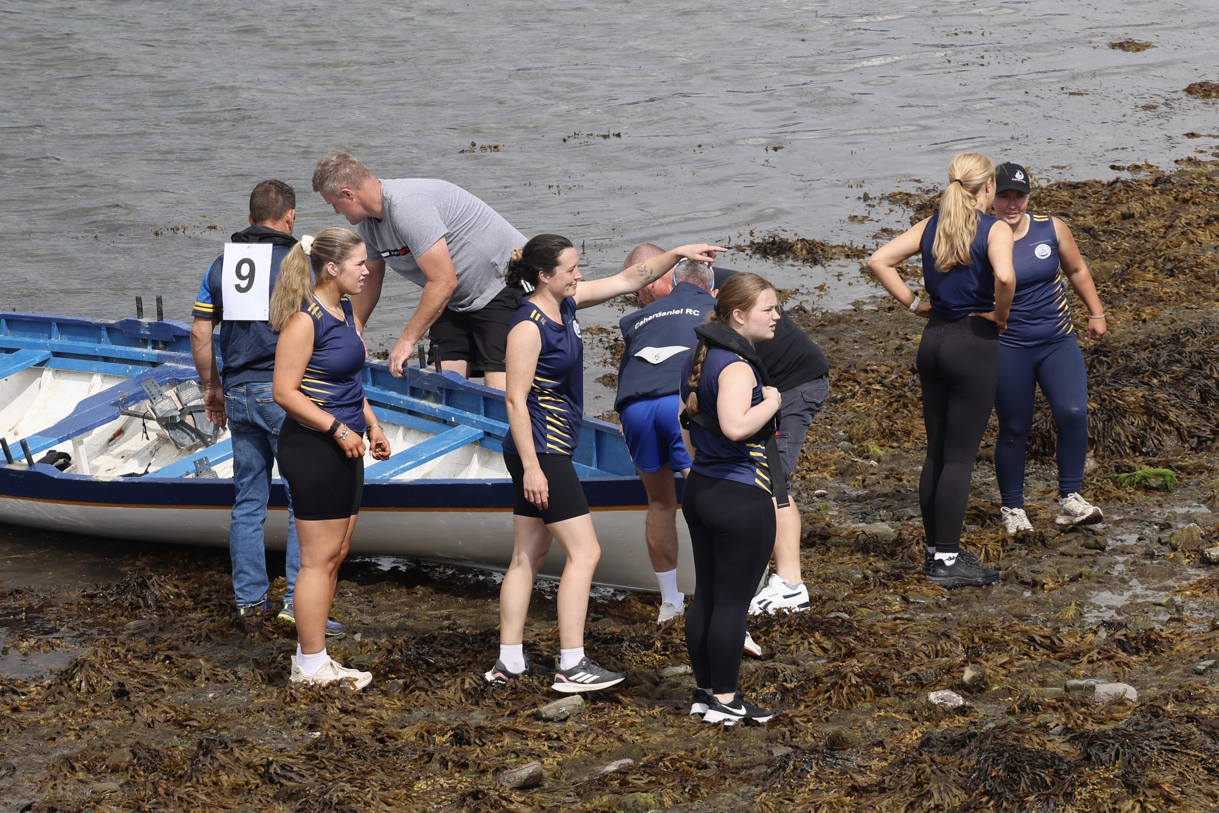 A women's rowing crew preparing beside the water
