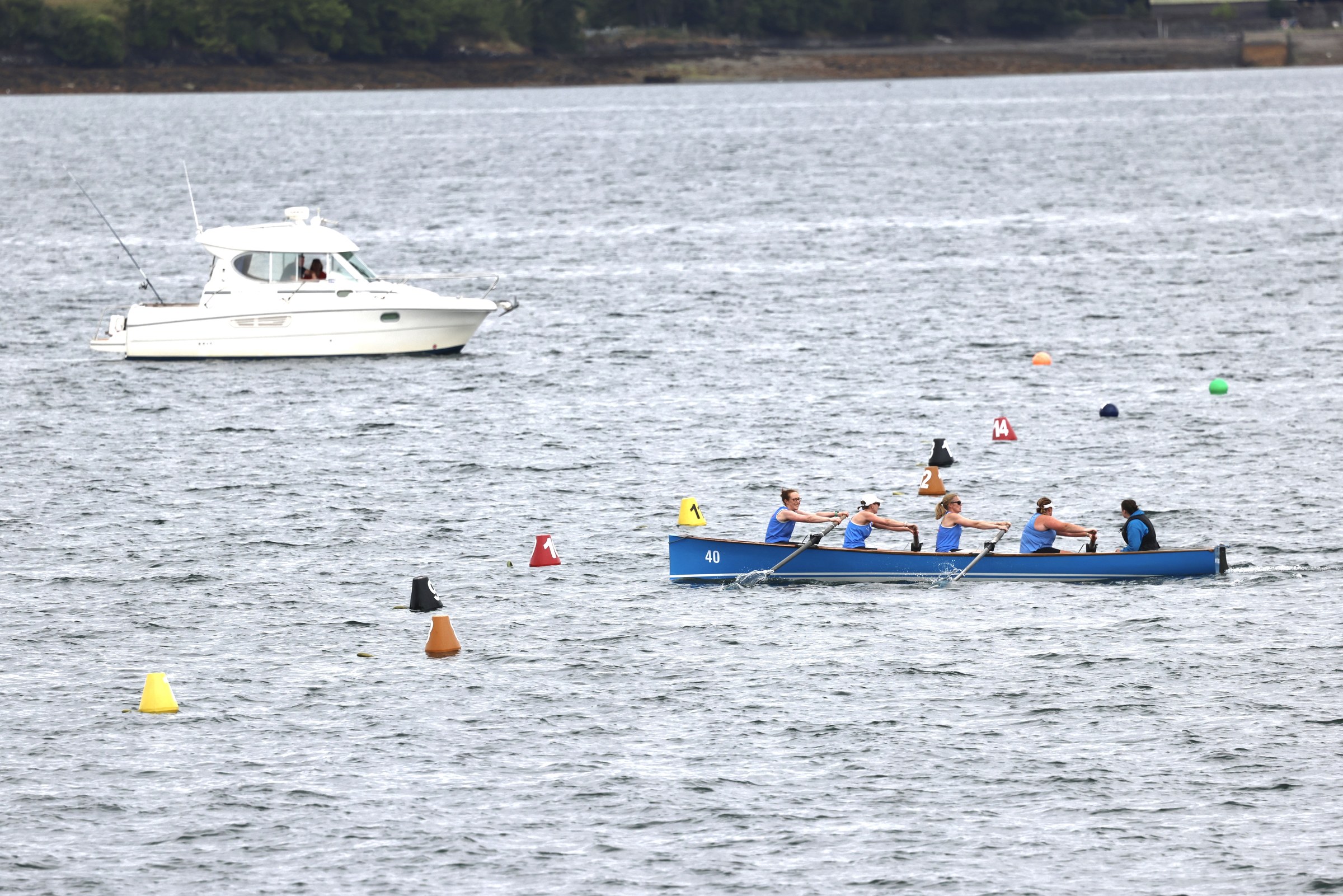 A blue rowing boat racing between marker buoys on Bantry Bay