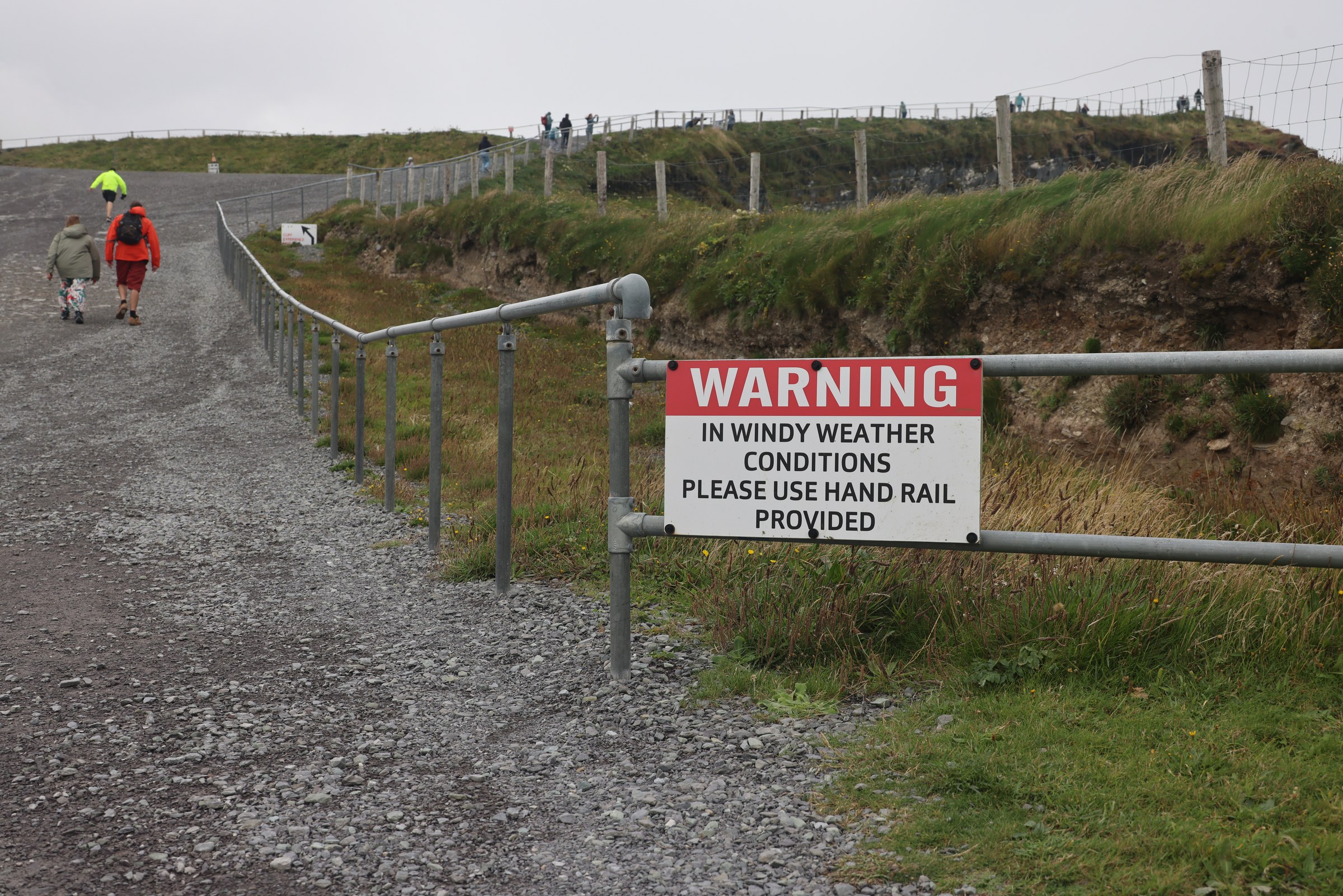 A warning sign advising visitors to use the handrail in windy weather