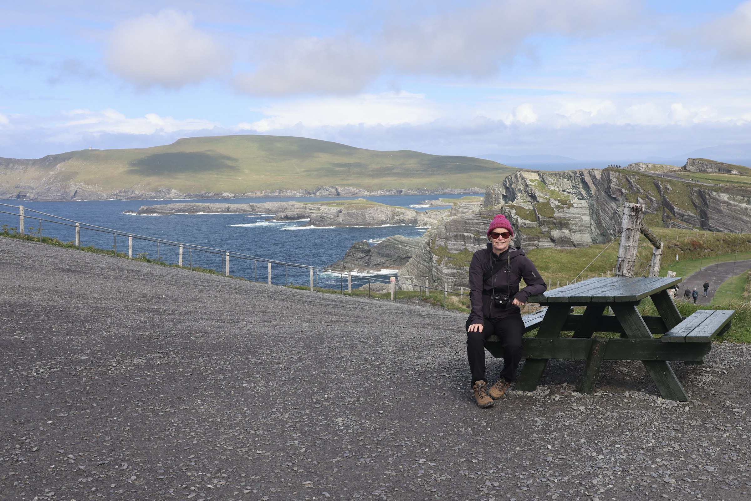 Sue beside a picnic table overlooking the Kerry Cliffs