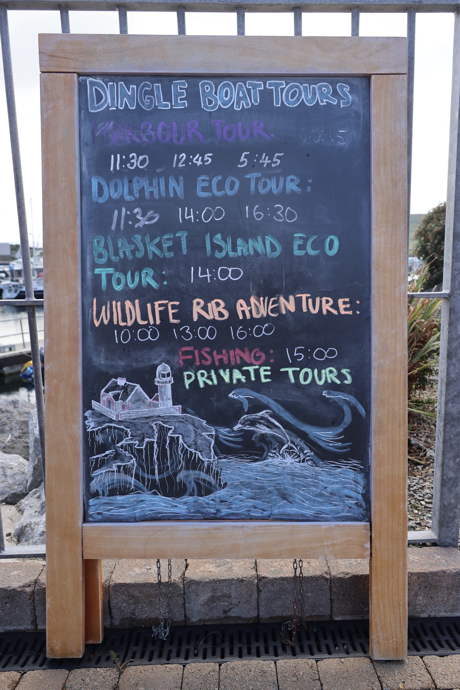 A chalkboard advertising Dingle Boat Tours trips beside the marina