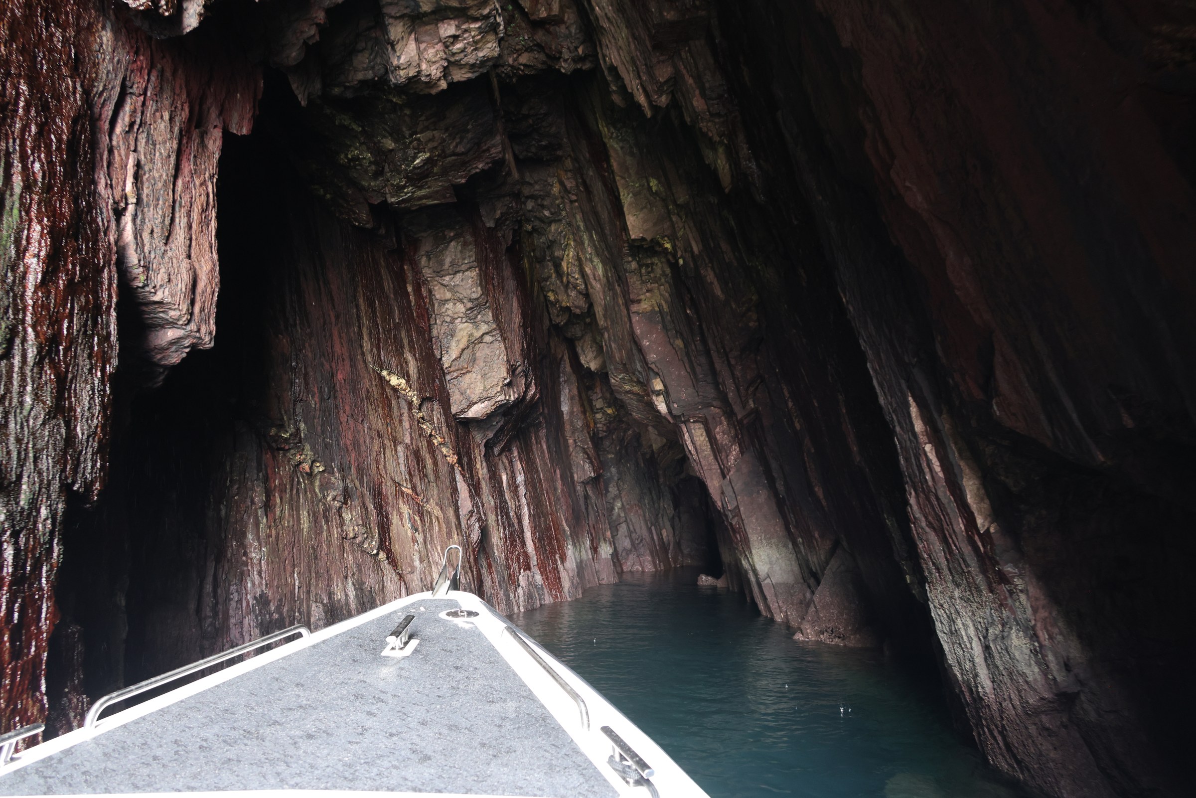 The bow of the RIB entering a dark sea cave in the Dingle cliffs