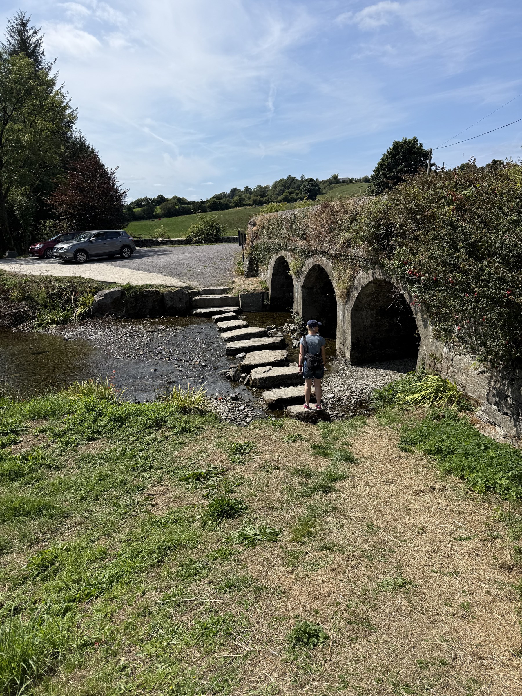 Stepping stones across the River Ilen beside an old stone bridge