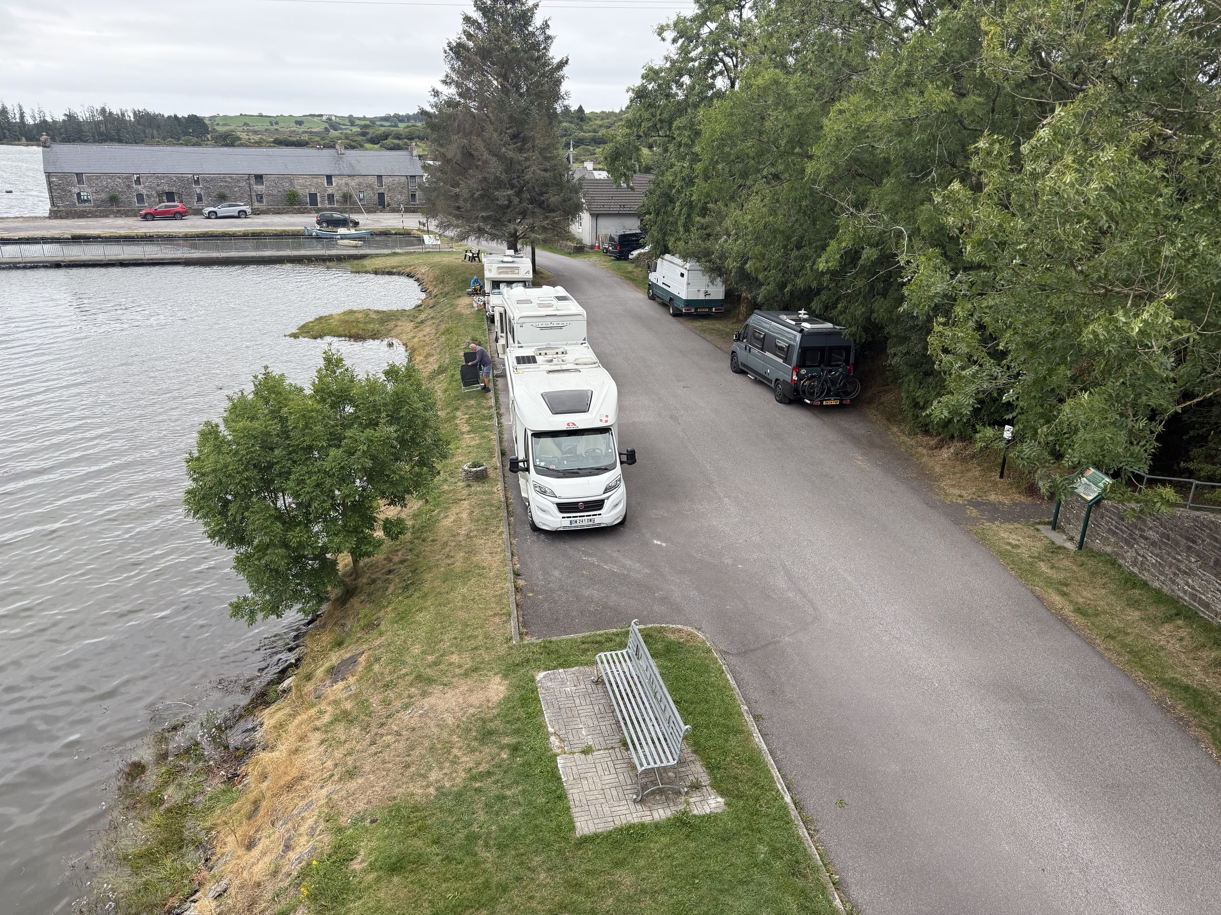 Campervans parked beside the water beneath Ballydehob's railway bridge