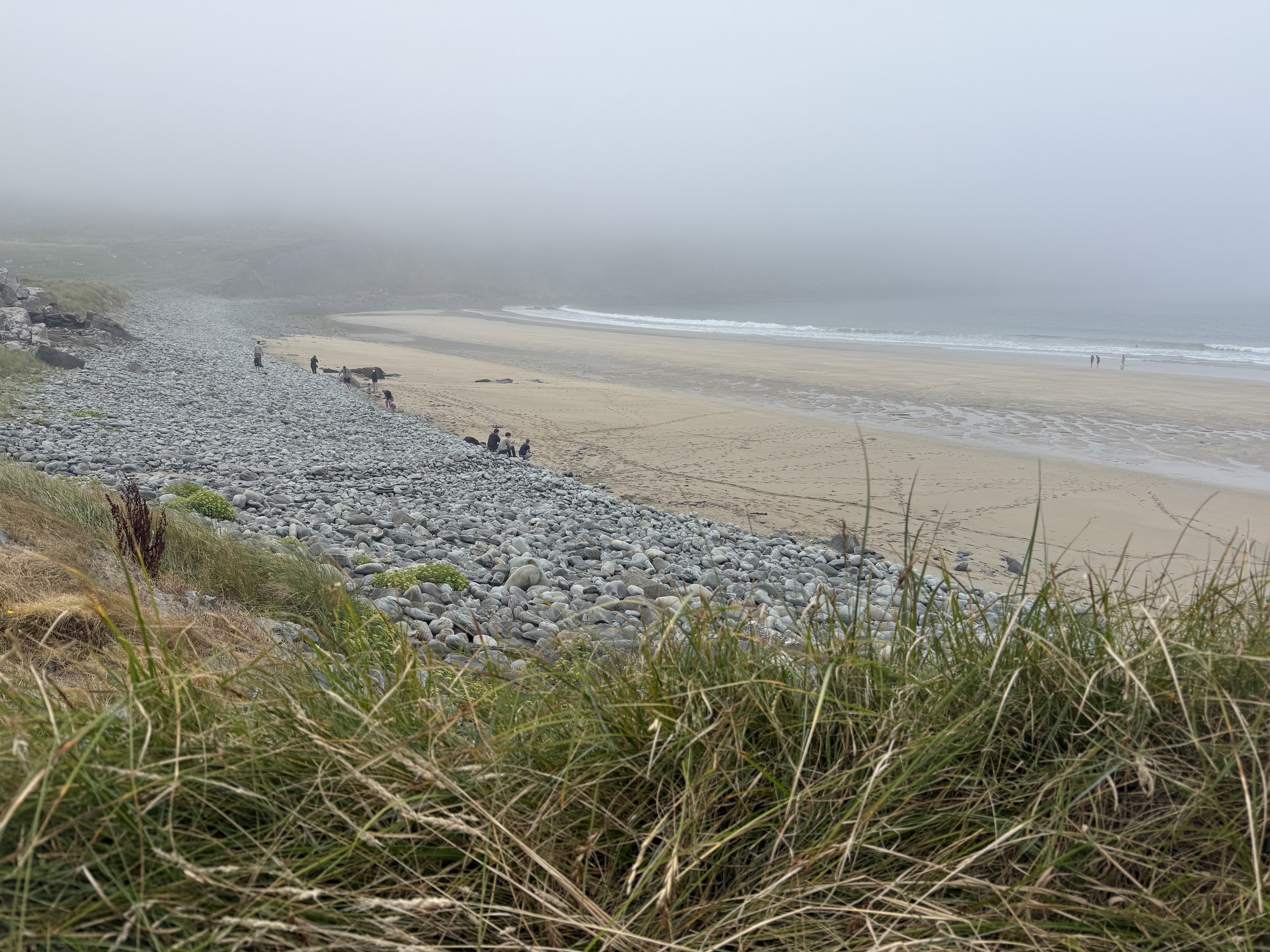 A sandy beach and turquoise water emerging through the mist