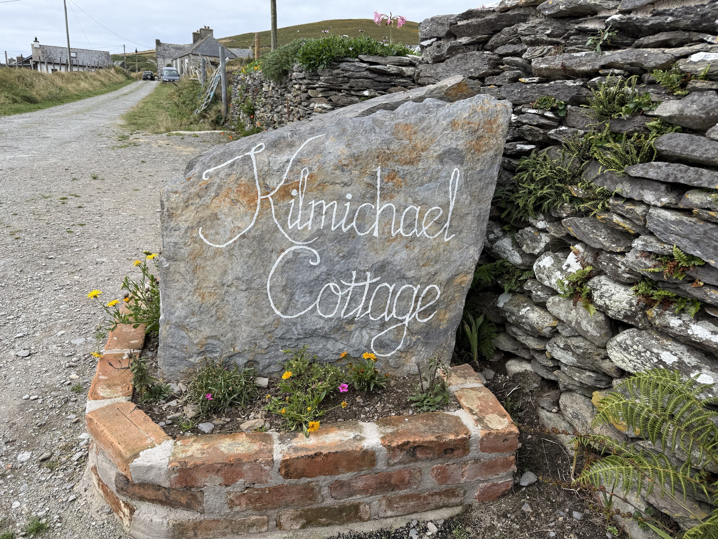 The hand-painted Kilmichael Cottage sign beside a stone wall
