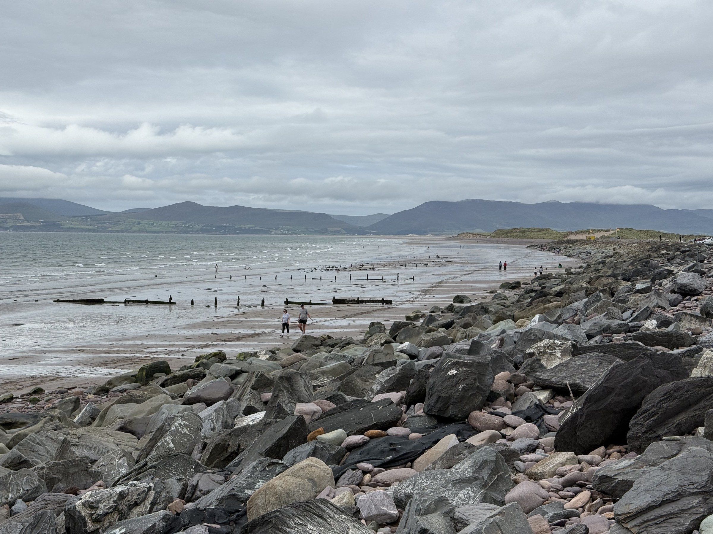 People walking among rocks on Rossbeigh Beach at low tide