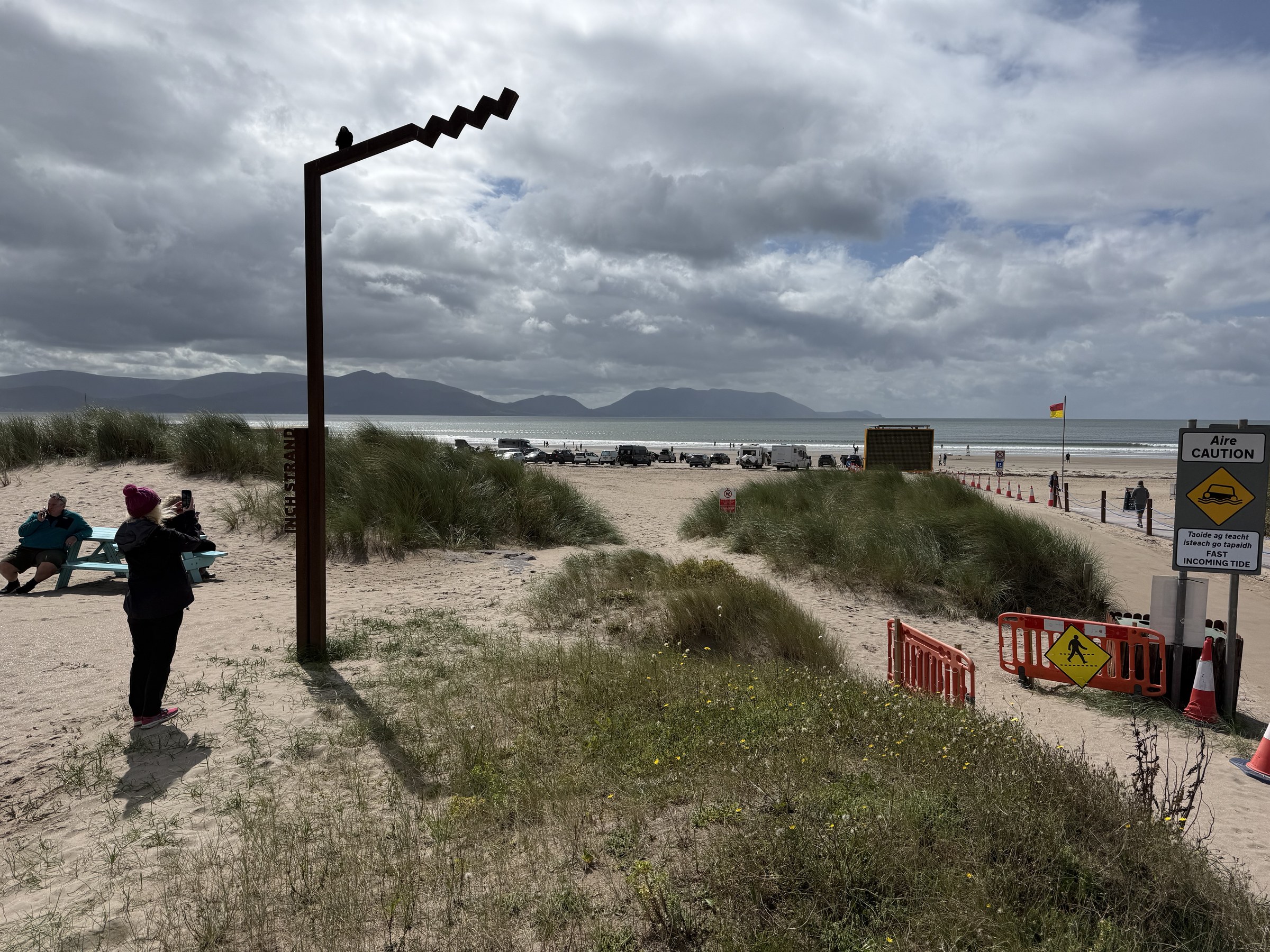 The entrance to Inch Beach with cars parked on the sand beyond the dunes