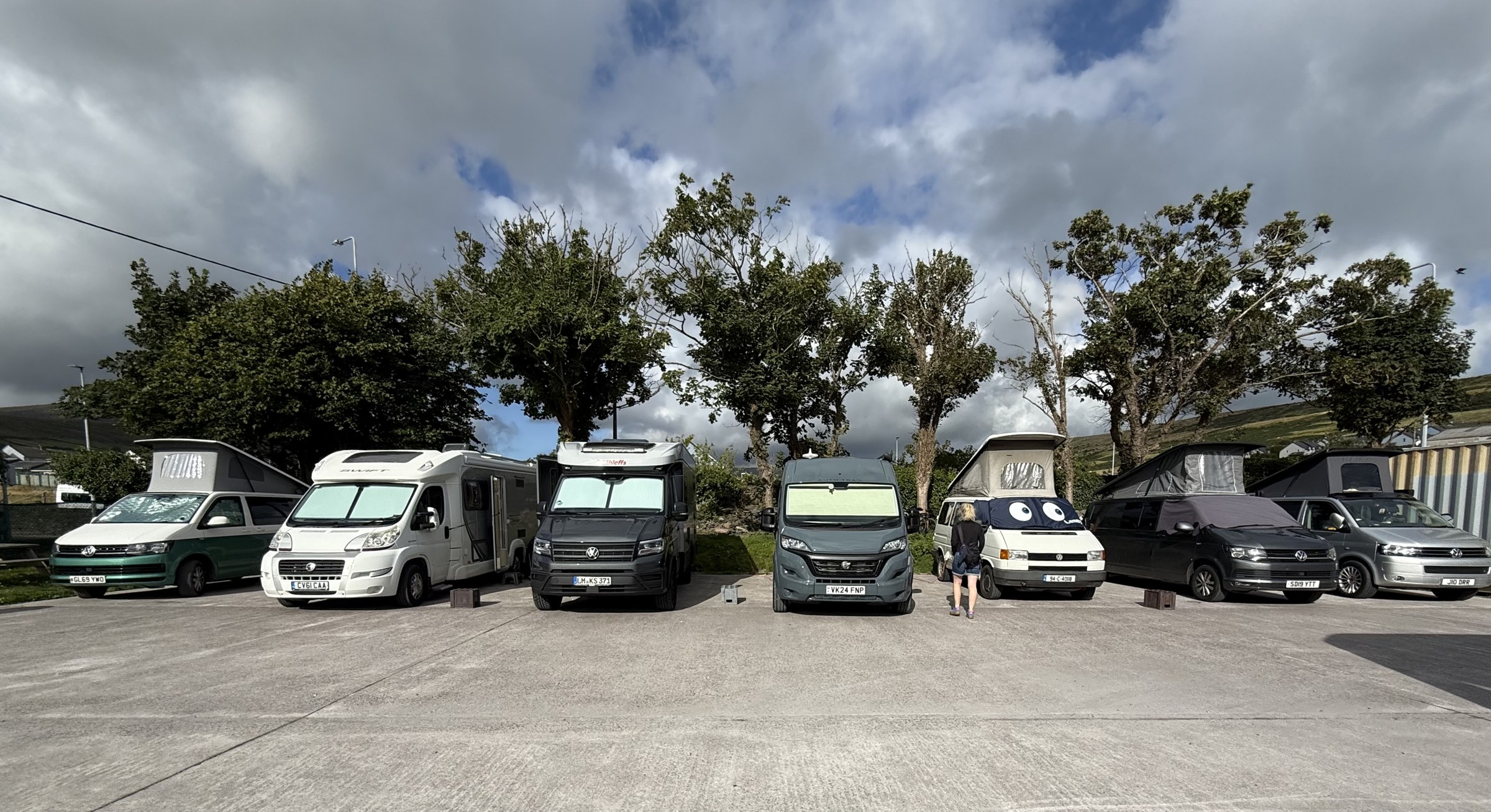 A row of campervans filling the pitches at Dingle Bridge House Camping