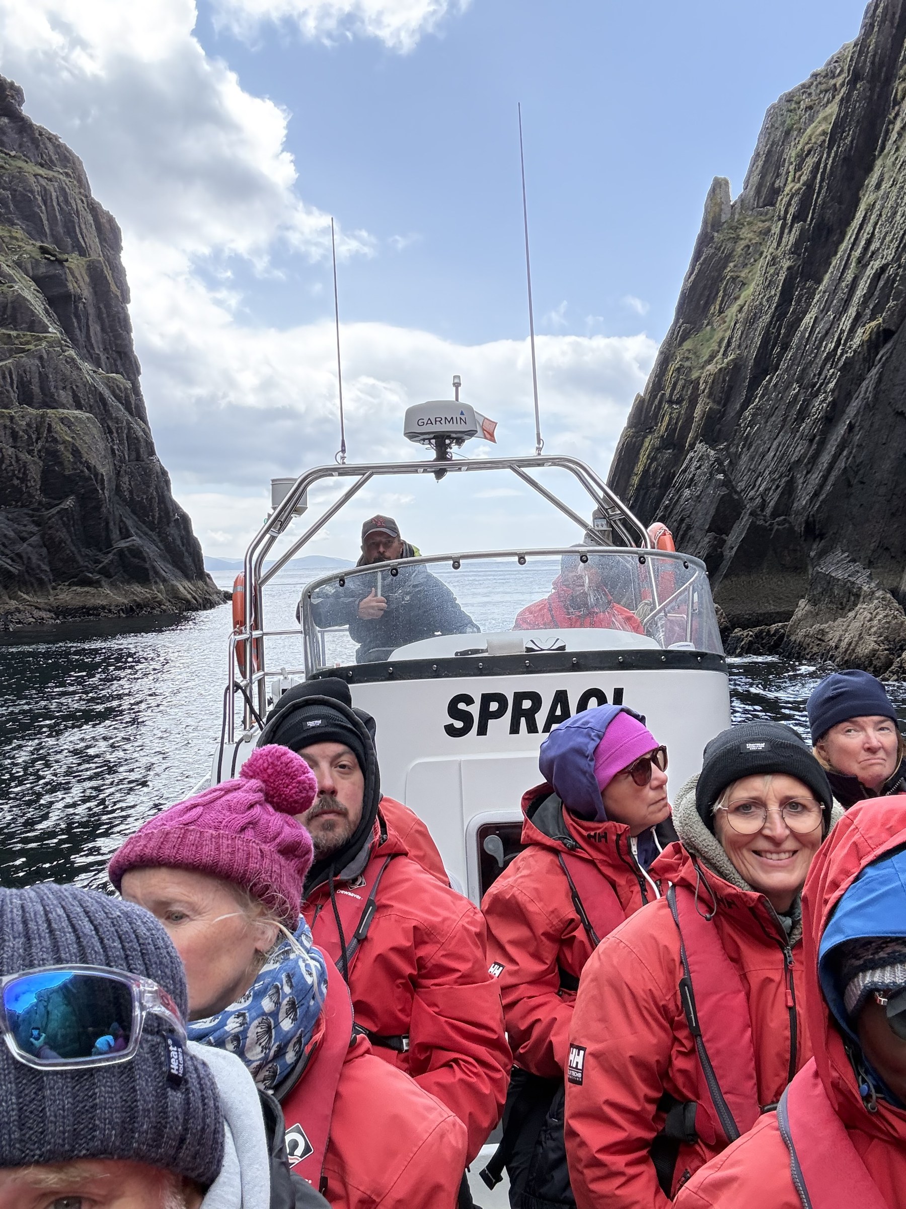 The waterproofed passengers aboard the RIB between steep cave walls