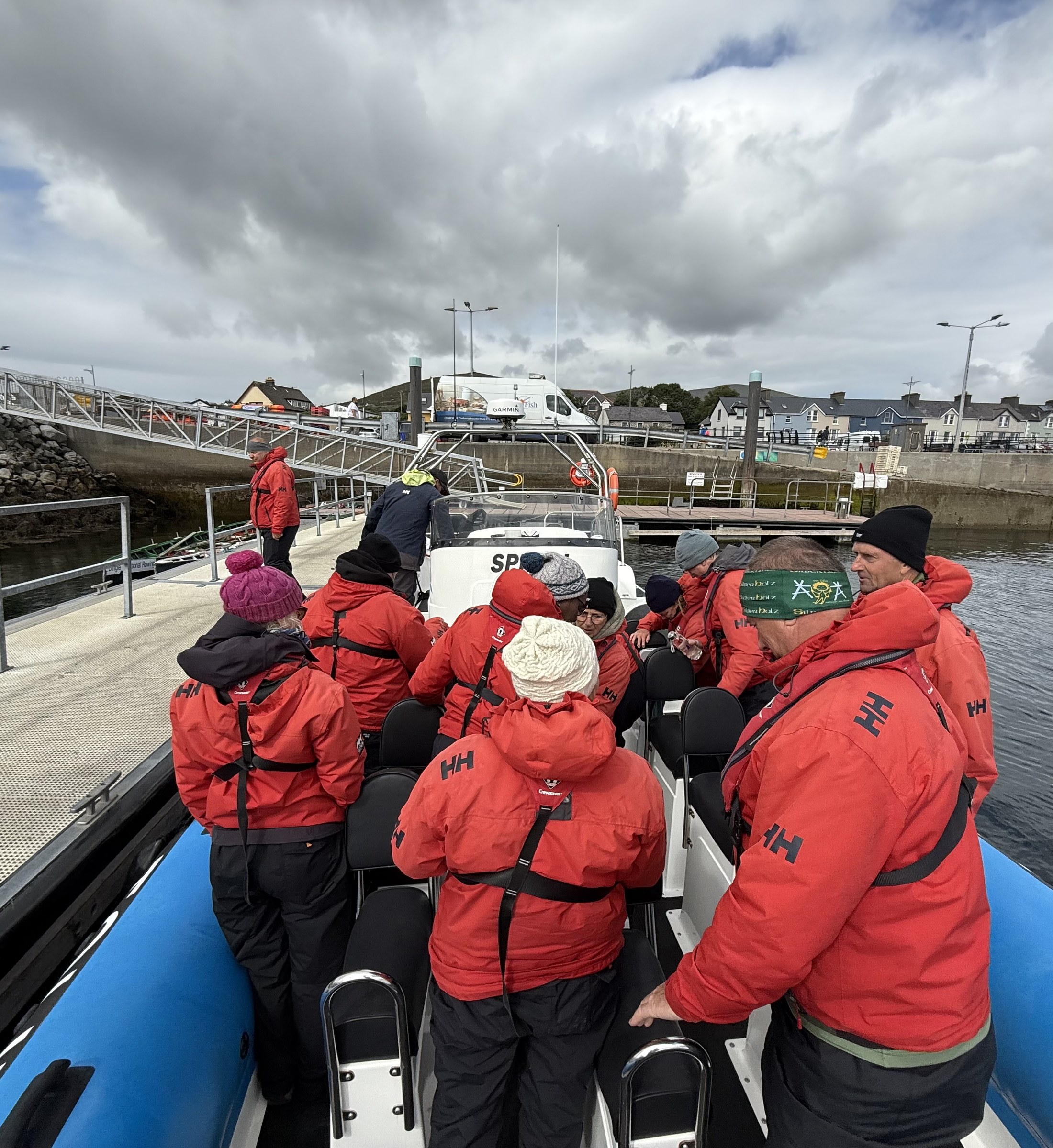 Passengers in red waterproofs sitting aboard the RIB as it returns to Dingle