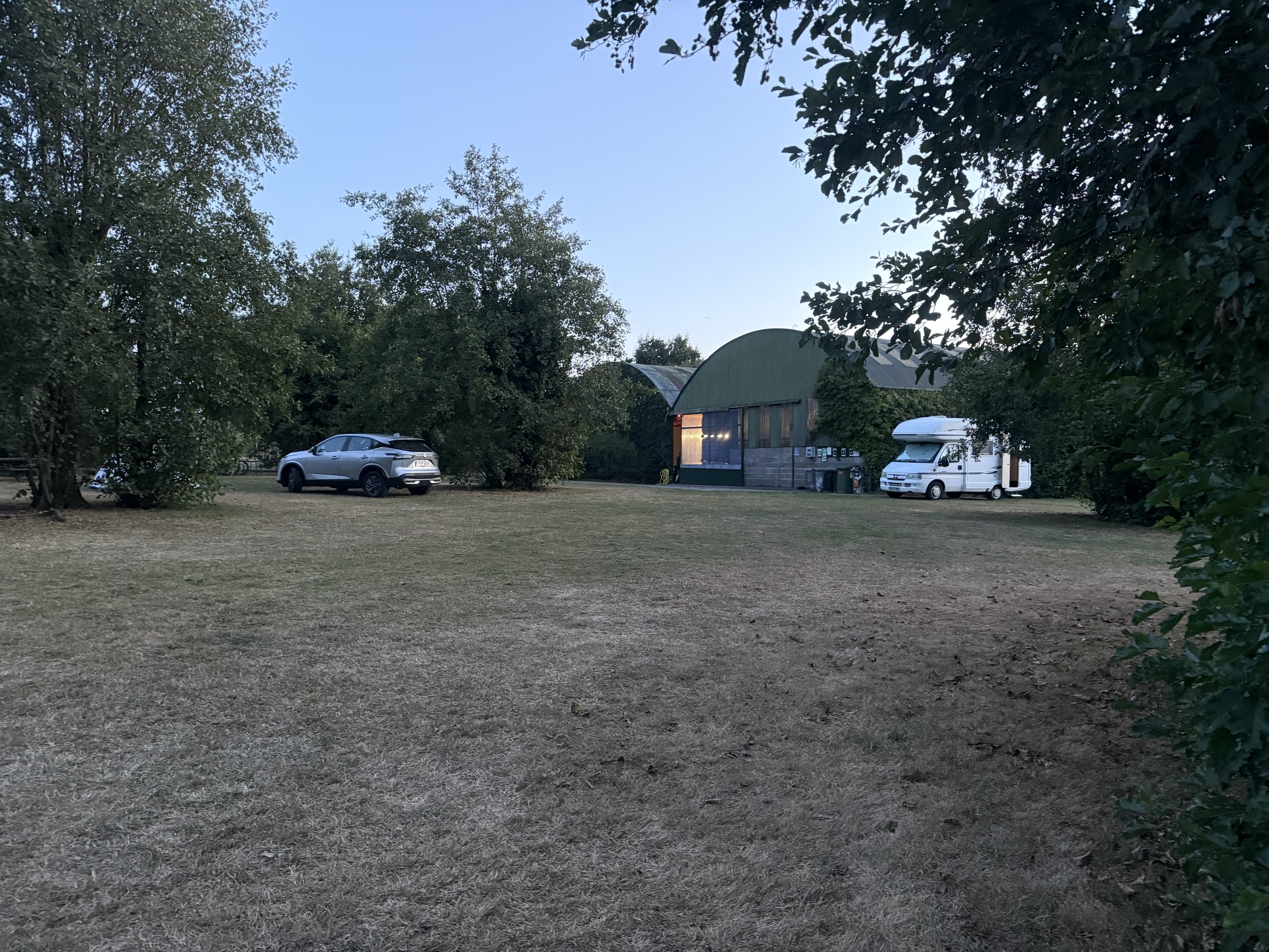 Campervans and the camping shed seen across the darkening campsite