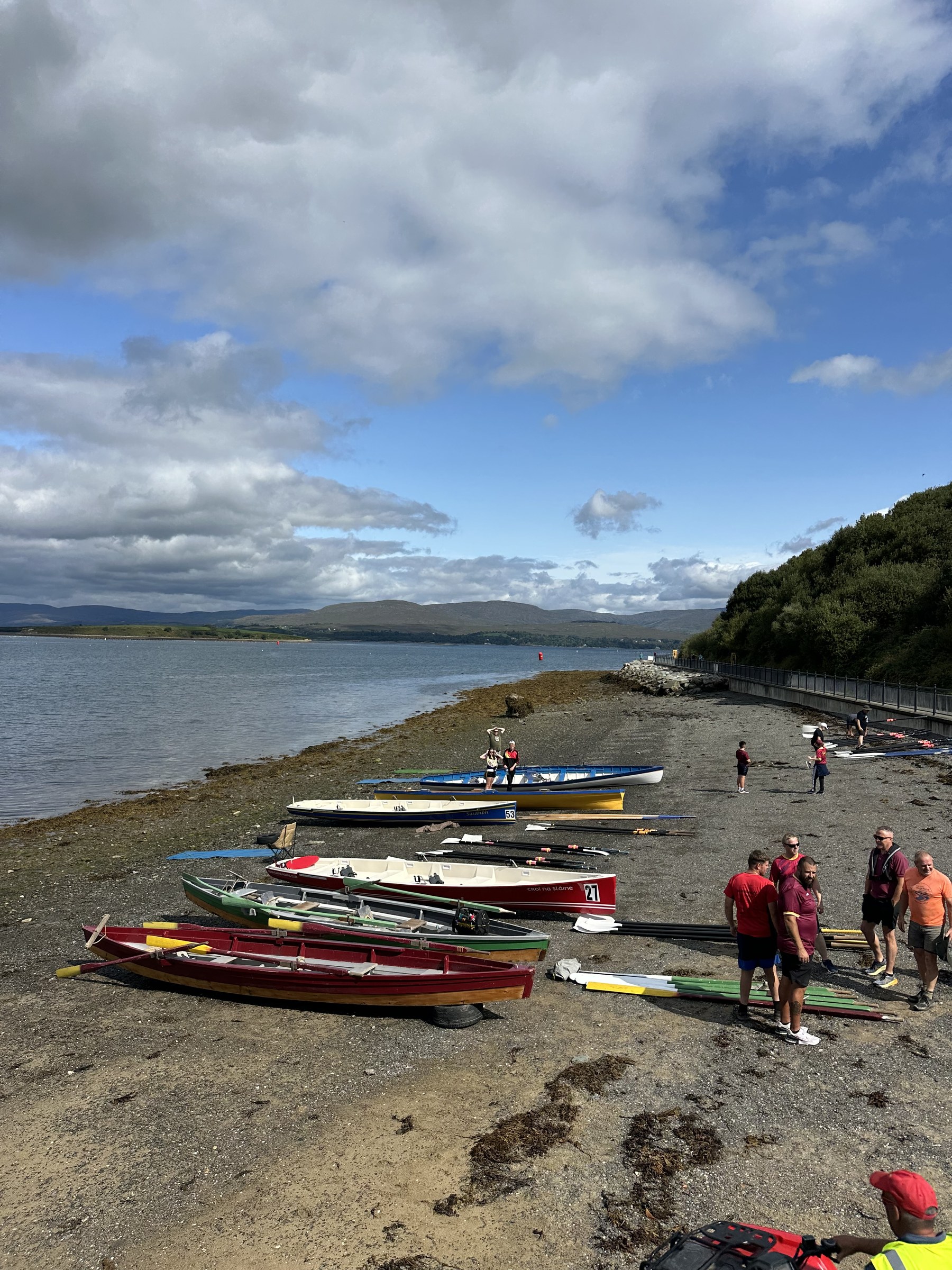 Rows of brightly coloured coastal rowing boats on the shoreline
