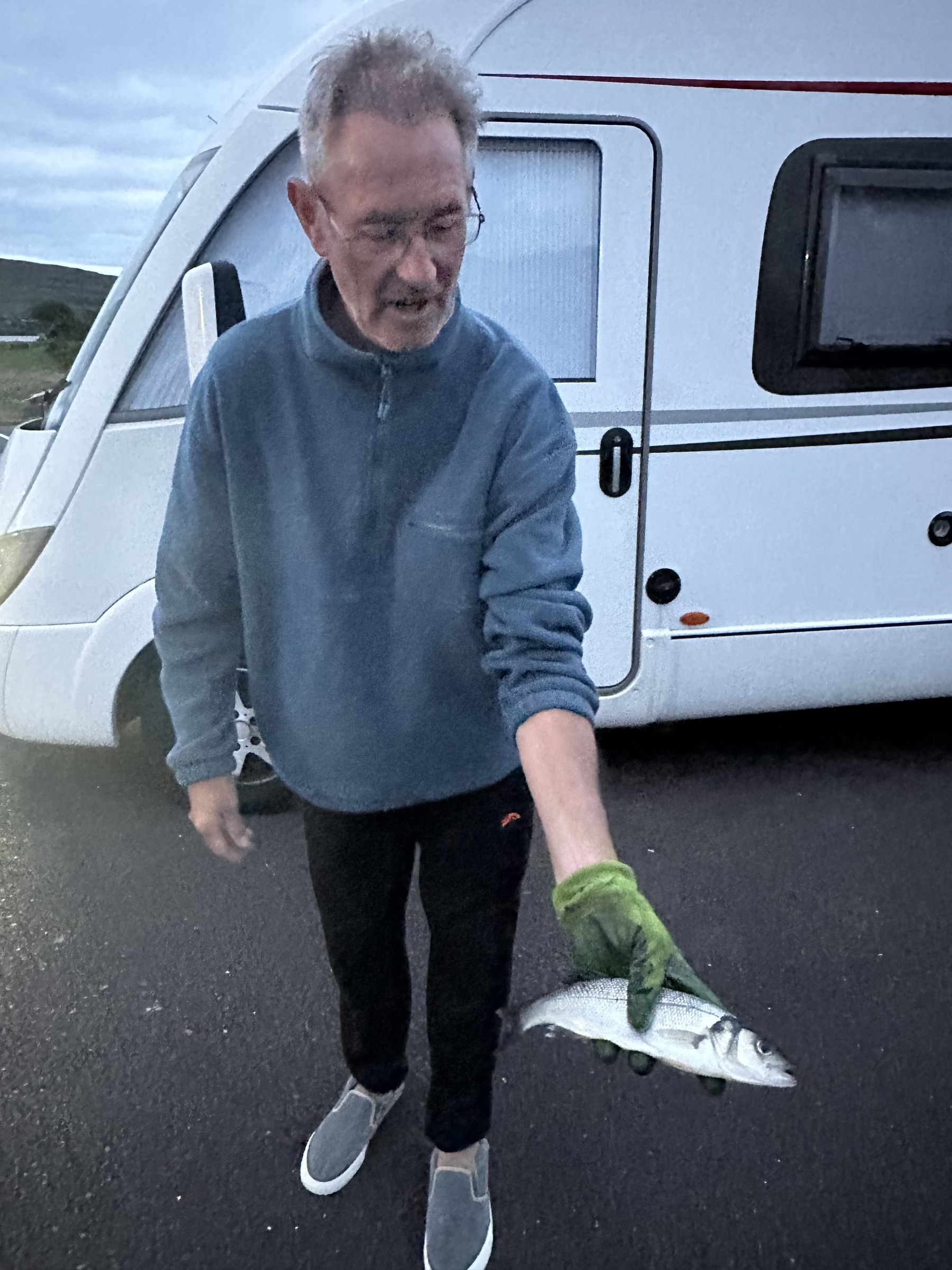 Roy holding the sea bass he caught beside the campervans