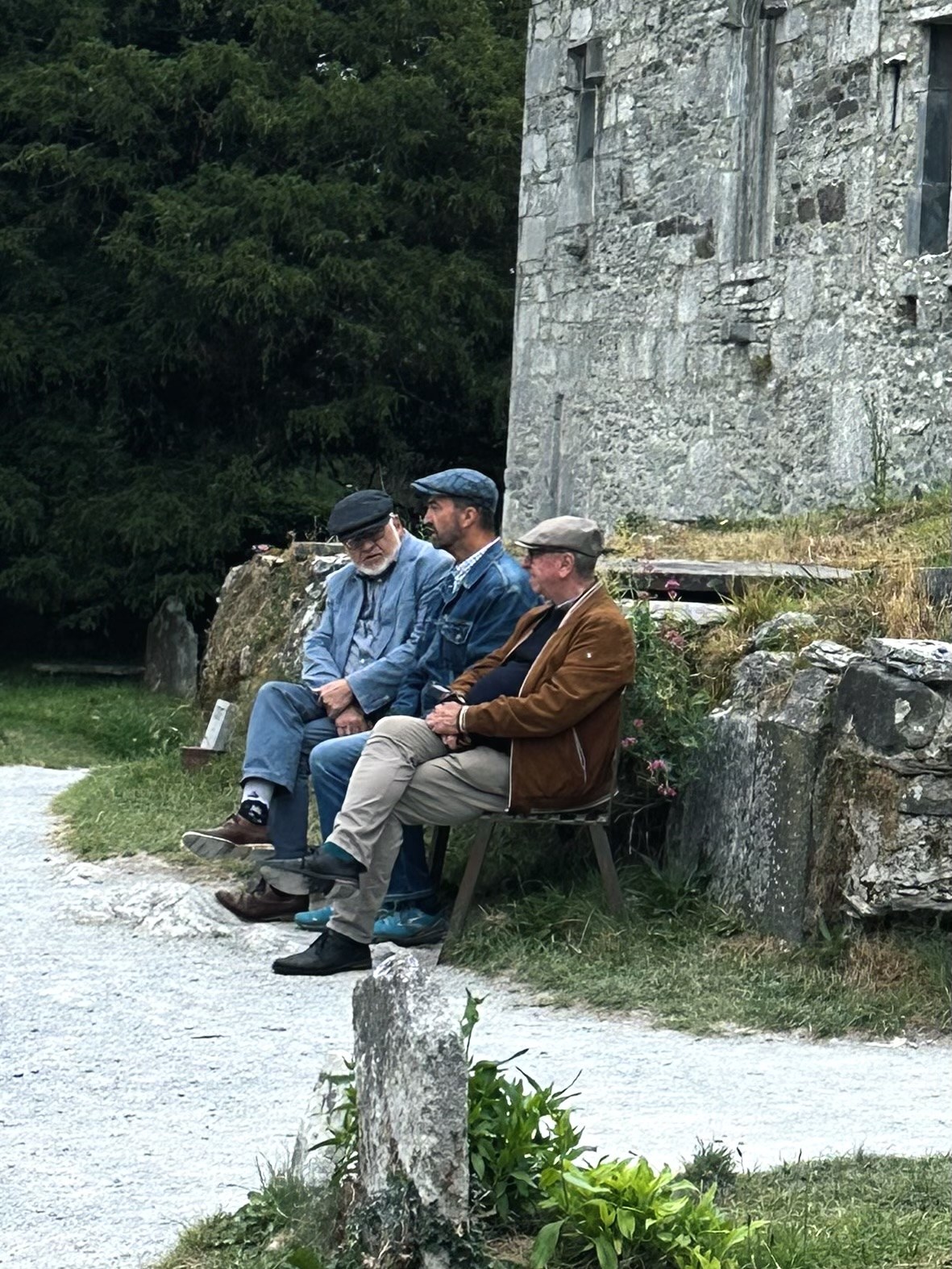 Three visitors sitting on a bench outside Muckross Abbey