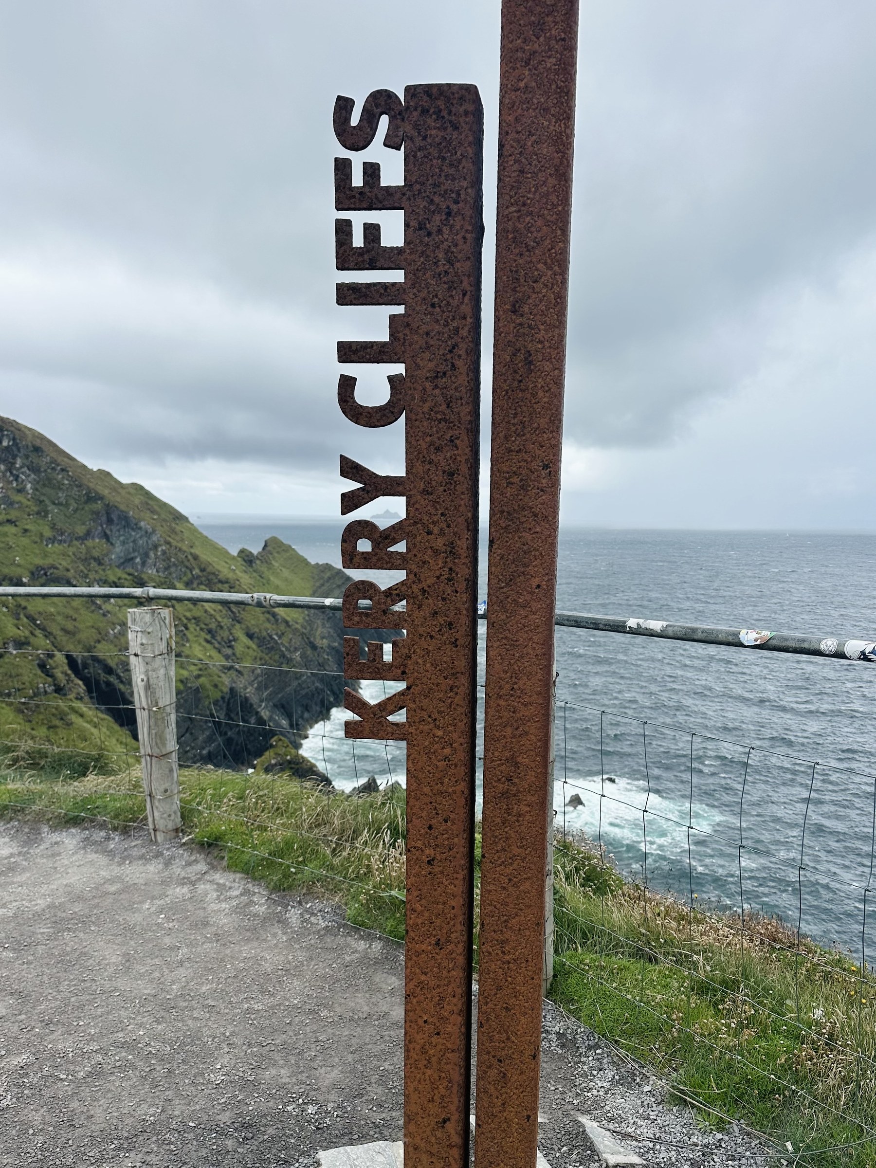 A rusted Kerry Cliffs marker beside the coastal path