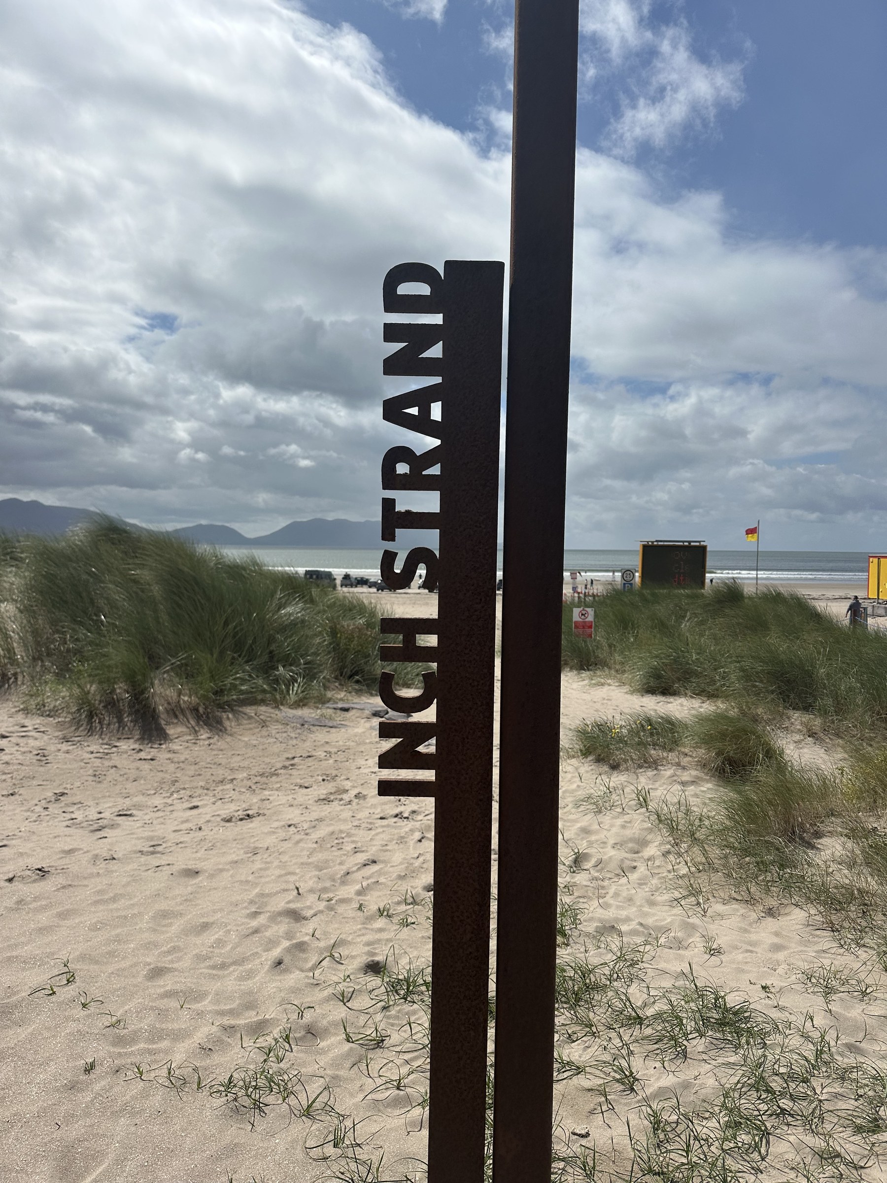 The rusted Inch Strand marker standing among the beach dunes