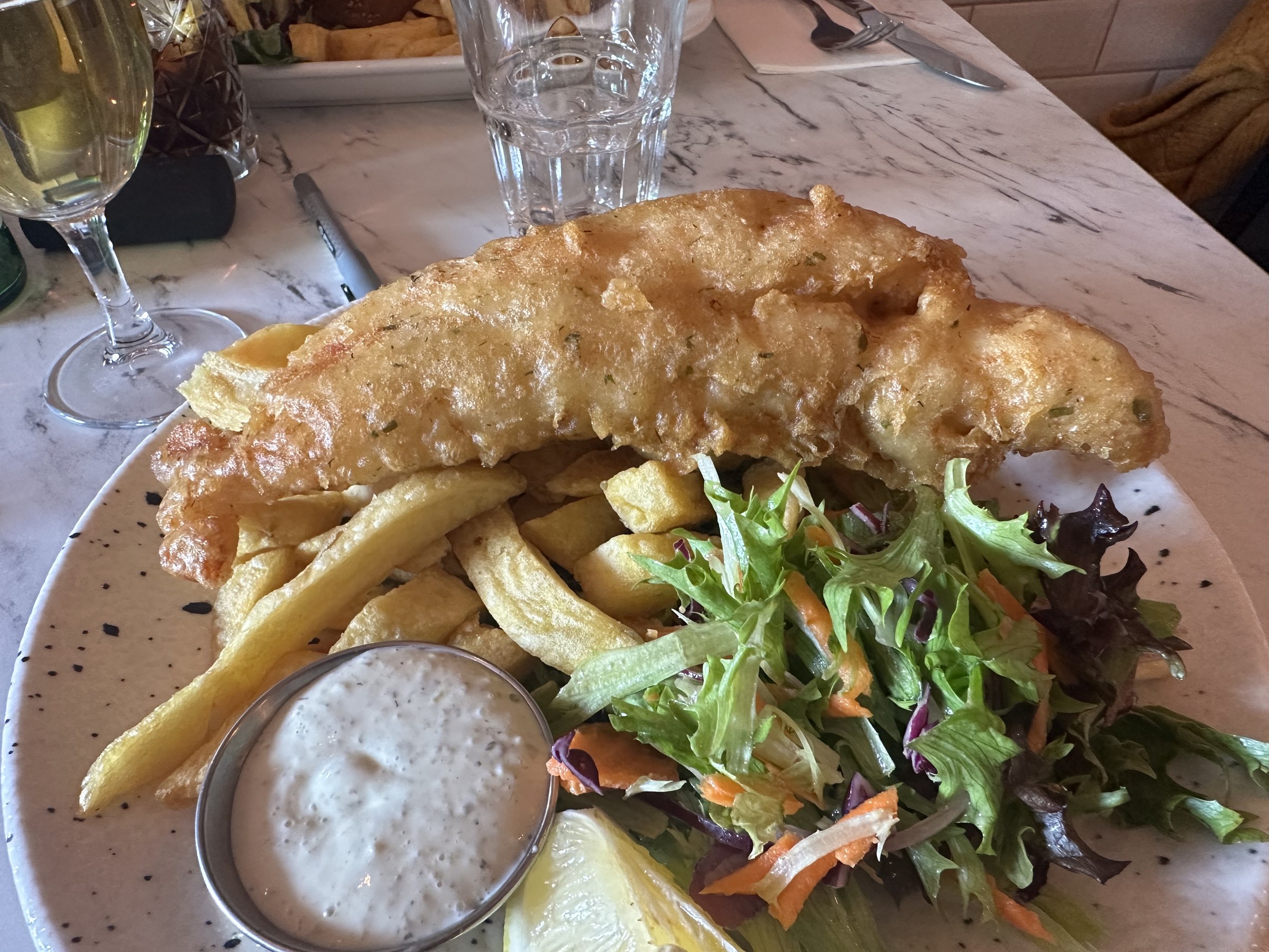 A large piece of battered fish served with chips and salad at The Fish Box