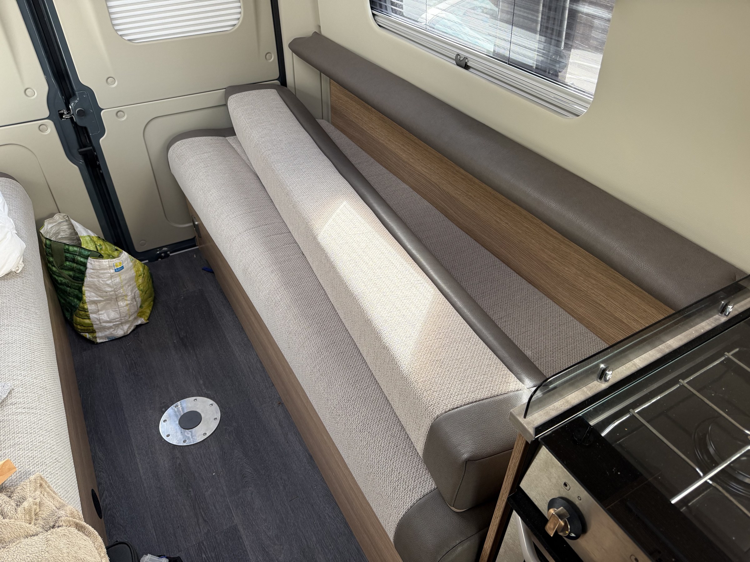 A bench seat being converted into a bed using its backrest bolster