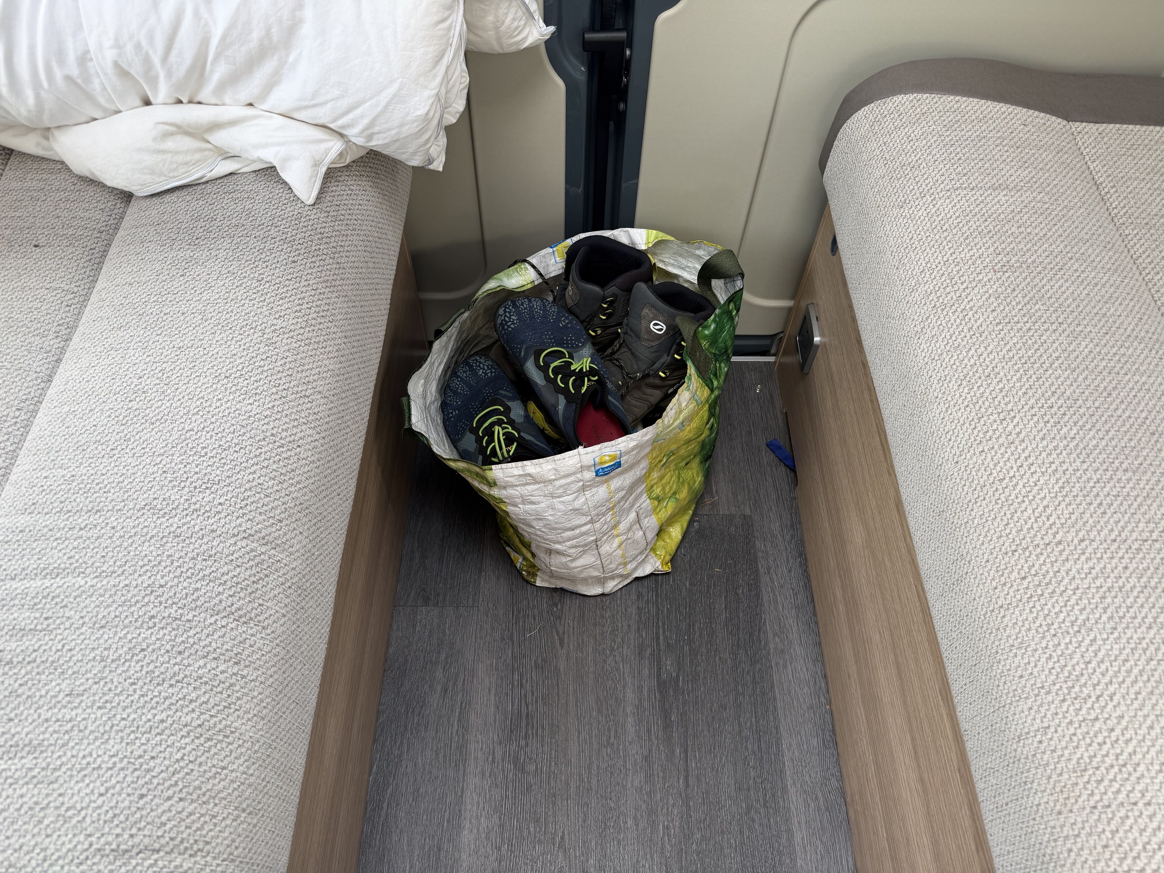 A bag of shoes occupying the walkway between the beds