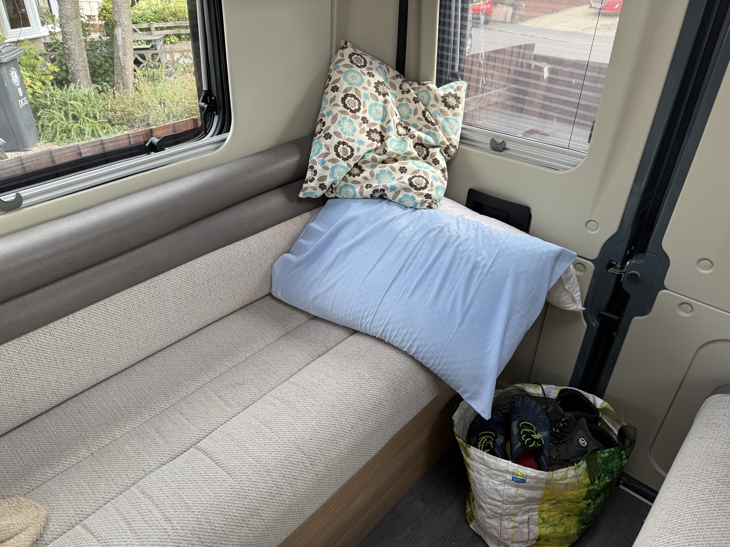 The sheet and duvet rolled up together at the end of one of the single beds