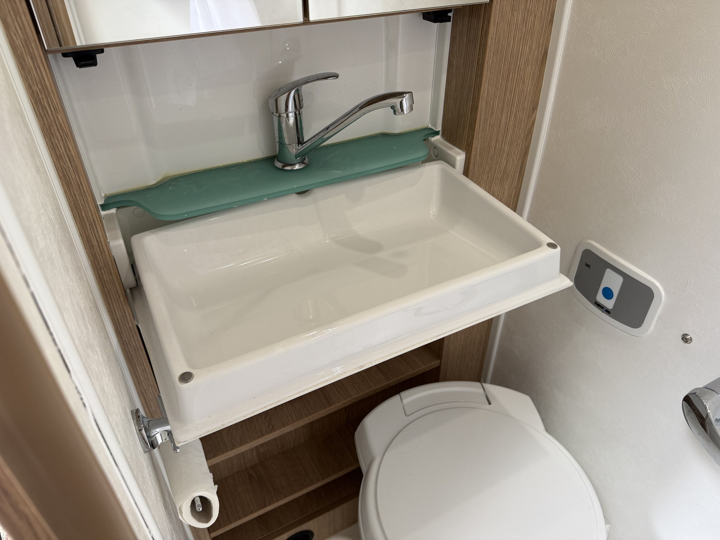 The bathroom basin tipped down into its open position