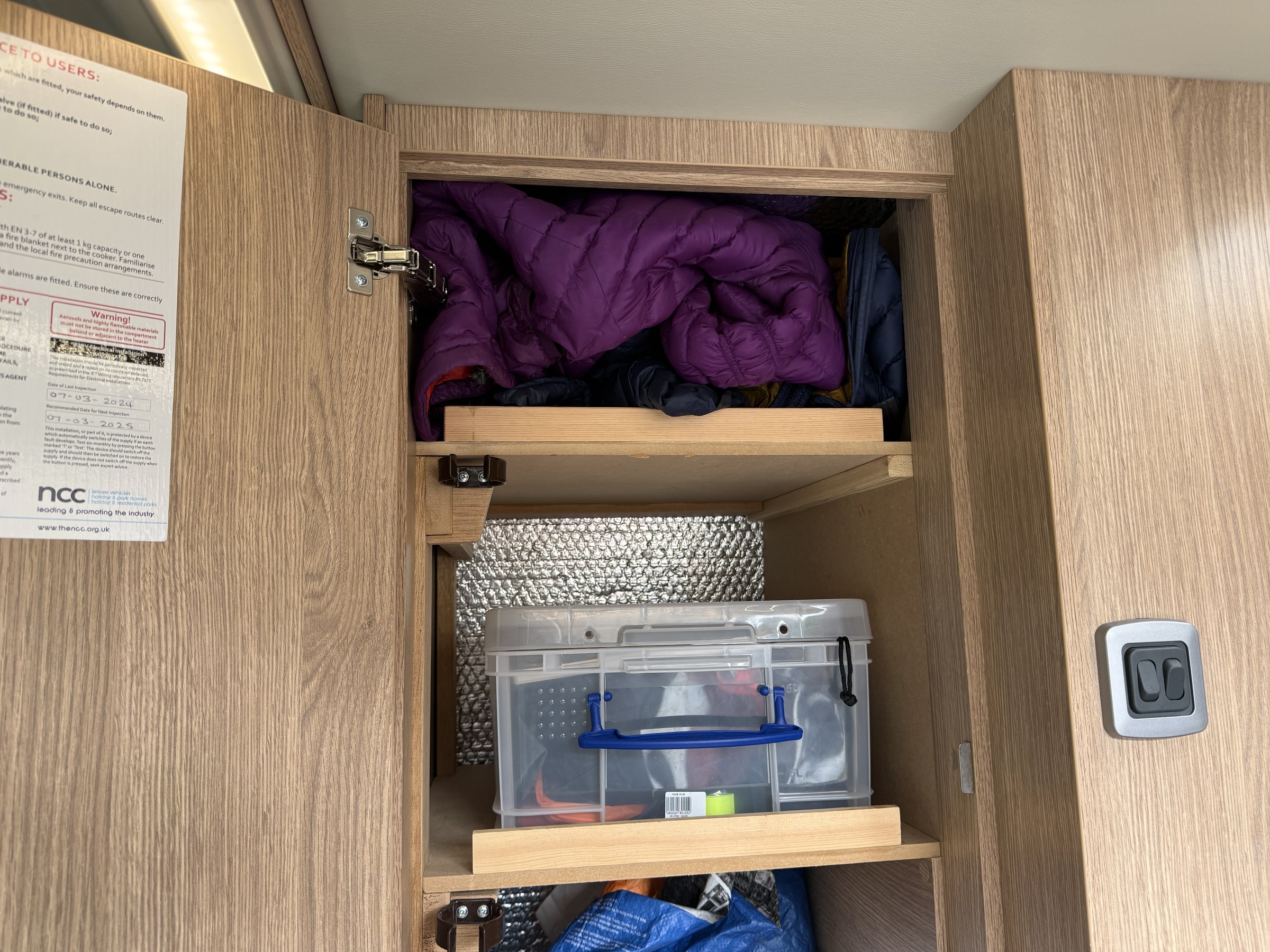 Coats stuffed into the small cupboard above the fridge