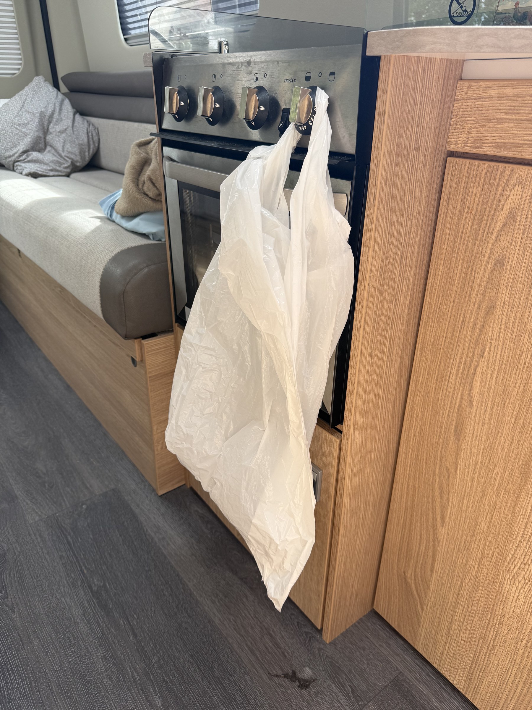 A rubbish bag hanging from one of the kitchen cupboard knobs